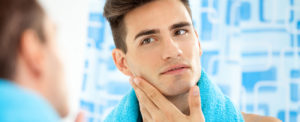 young man touching his face while looking in the mirror